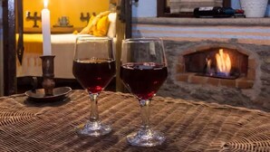 Two glasses of red wine on a woven table with a lit candle and a fireplace in the background. - Best Price Suite w/ bathroom, terrace, peaceful and private (Valle de Bravo)