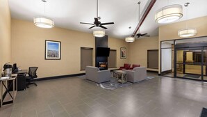 A lobby with a fireplace, ceiling fans, and a seating area with chairs and a table. - Super 8 by Wyndham Alexandria LA (Alexandria)