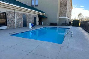 A rectangular outdoor swimming pool with a metal ladder, surrounded by a concrete deck. - Super 8 by Wyndham Alexandria LA (Alexandria)