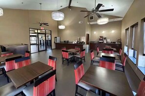 A hotel lobby with multiple dining tables, chairs, ceiling fans, and a coffee station. - Super 8 by Wyndham Alexandria LA (Alexandria)