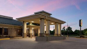 A building with a covered entrance, columns, and a parking lot. - Super 8 by Wyndham Alexandria LA (Alexandria)