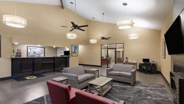 A hotel lobby with a reception desk, seating area, ceiling fans, and a television. - Super 8 by Wyndham Alexandria LA (Alexandria)