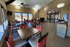 A restaurant with booths and tables, ceiling fans, and large windows. - Super 8 by Wyndham Alexandria LA (Alexandria)