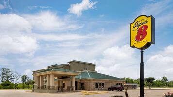 A hotel with a large sign reading 'Super 8 by Wyndham,' a covered parking area, and a building with a green roof.