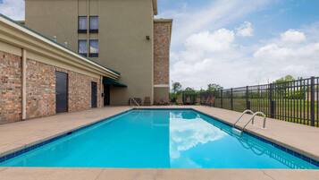 A swimming pool with a brick wall and a building in the background.