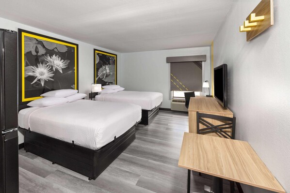 A hotel room with two beds, a desk, a TV, and artwork on the walls. - Super 8 by Wyndham Alexandria LA (Alexandria)