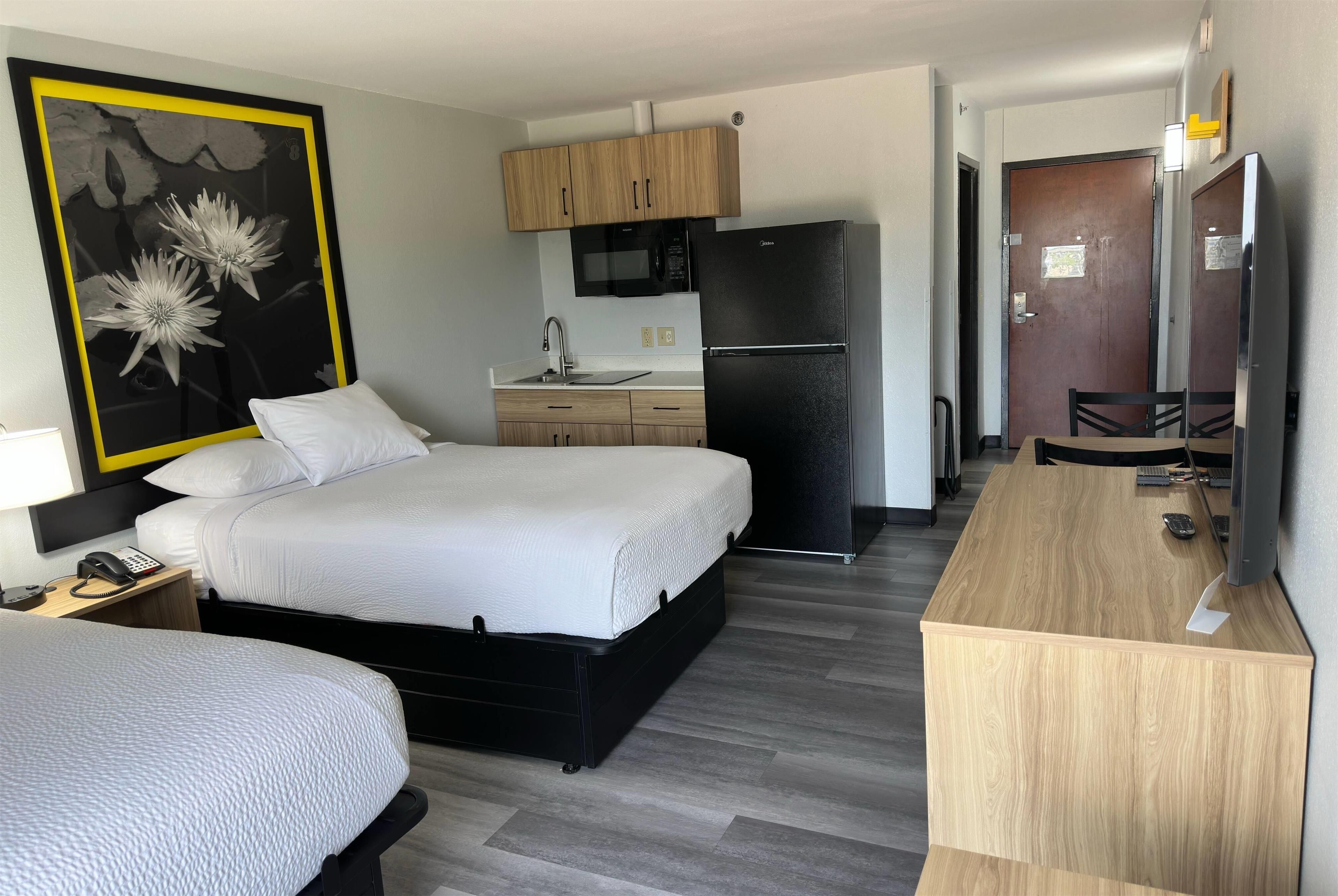 A hotel room with a bed, a desk, a microwave, a refrigerator, and a bathroom.