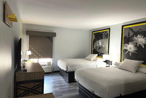 A hotel room with two beds, a desk, a chair, a TV, and artwork on the walls. - Super 8 by Wyndham Alexandria LA (Alexandria)