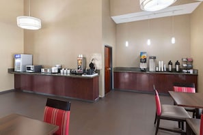 Un hall d’hôtel comprenant un comptoir d’accueil, un espace salon et des machines à café.
