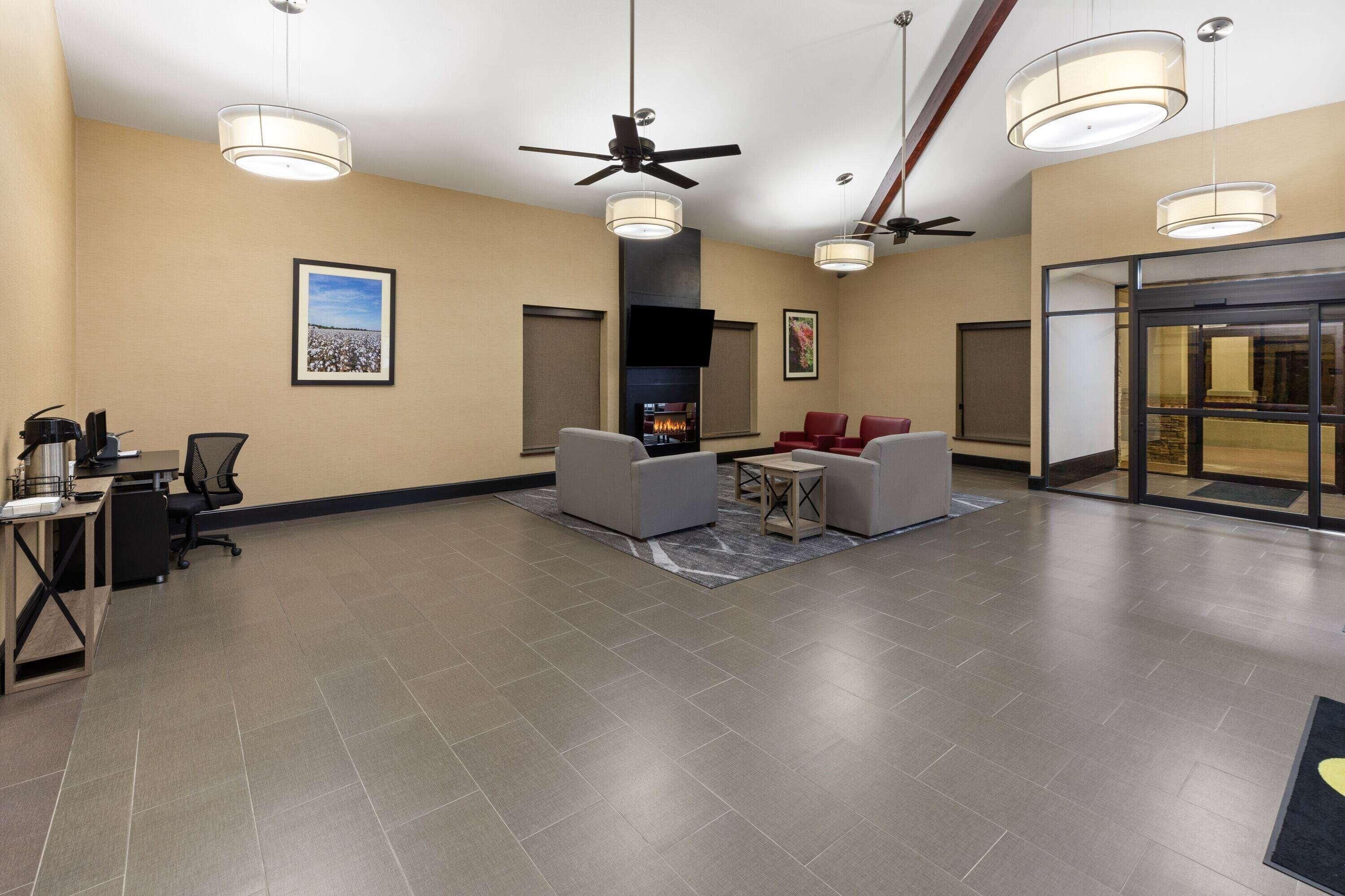 A lobby with a fireplace, ceiling fans, and a seating area with chairs and a table.