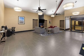 A lobby with a fireplace, ceiling fans, and a seating area with chairs and a table. - Super 8 by Wyndham Alexandria LA (Alexandria)