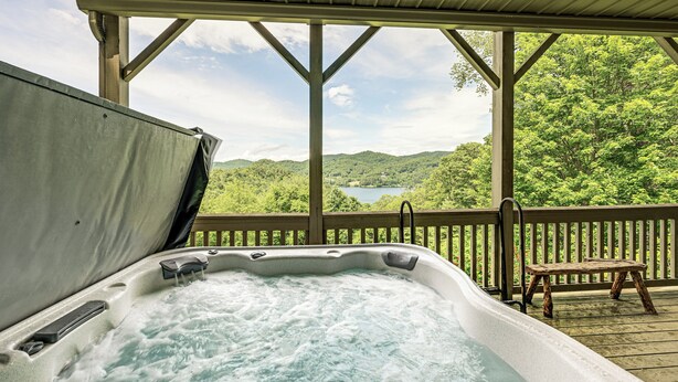 A hot tub with a wooden deck and a view of a lake surrounded by trees. - Water Views! Group-Friendly Lake Glenville Home (Cullowhee)