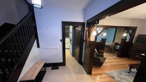Een modern interieur met een houten trap, een bank, een eethoek met tafel en stoelen, en een woonkamer met televisie.
