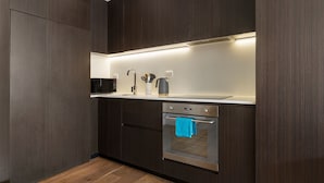 Une cuisine moderne avec des meubles en bois foncé, un four en acier inoxydable, un four à micro-ondes et un évier encastré.