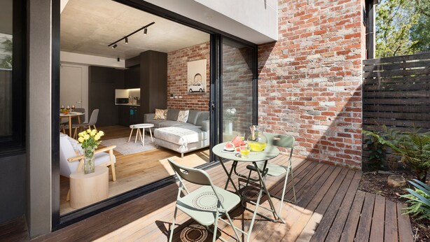 Un espace de vie moderne comprenant un coin repas, une cuisine et un patio aménagé avec du mobilier d’extérieur.