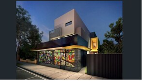 Un bâtiment moderne à deux étages, doté d’un toit plat, d’une grande fresque sur l’un de ses murs et d’une entrée sécurisée par un portail.