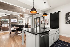 Una cucina moderna con isola centrale, lampade pendenti nere e un ampio specchio con cornice nera.