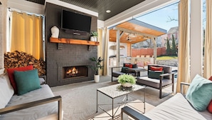 A modern living room with a fireplace, comfortable seating, and a television mounted on the wall. - The Blue Note - Luxe Outdoor Retreat & Pool - Close to Downtown (Nashville)