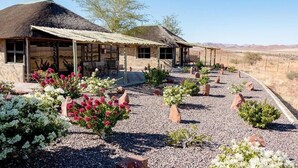 A rustic building with a thatched roof, surrounded by a gravel garden with various plants and flowers. - Mountain View Villa (Pacific Harbour)