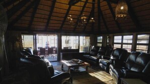 A spacious living area with leather sofas and a coffee table, large windows providing natural light, and a high ceiling with exposed beams. - Mountain View Villa (Pacific Harbour)