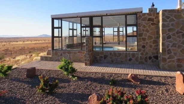 A modern stone building with large glass windows and a pool area. - Mountain View Villa (Pacific Harbour)