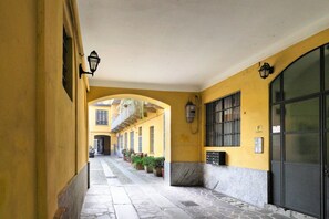 Un estrecho callejón con edificios amarillos, suelo de piedra y plantas al aire libre.