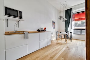 Una cocina moderna con microondas, fregadero y encimera de madera. Cuenta con un comedor con mesa y sillas.