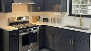 Una cocina moderna con armarios oscuros, electrodomésticos de acero inoxidable y un ventanal que proporciona luz natural.