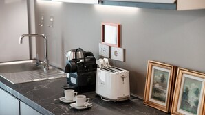A kitchen with a coffee maker, toaster, and framed pictures on the counter. - Numero 11 Piazza Amendola - My Home in Como (Como)