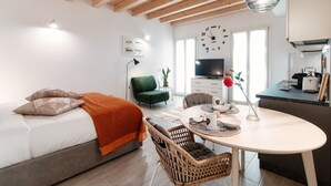 A modern, well-lit room with a bed, a dining table, and a kitchen area. - Numero 11 Piazza Amendola - My Home in Como (Como)