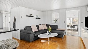 Ein modernes Wohnzimmer mit einem grauen Ecksofa, einem weißen Couchtisch und einem flauschigen grauen Pouf.