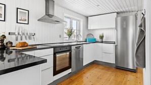 Eine moderne Küche mit weißen Schränken, Edelstahlgeräten und Holzboden.