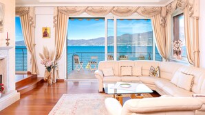 Un salon spacieux avec un grand canapé, une table basse et une vue sur la mer, accessible par une porte-fenêtre coulissante.