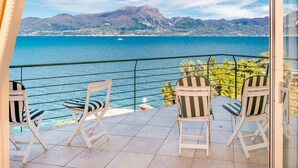 Un balcon avec des chaises blanches et une vue sur la mer et les montagnes.