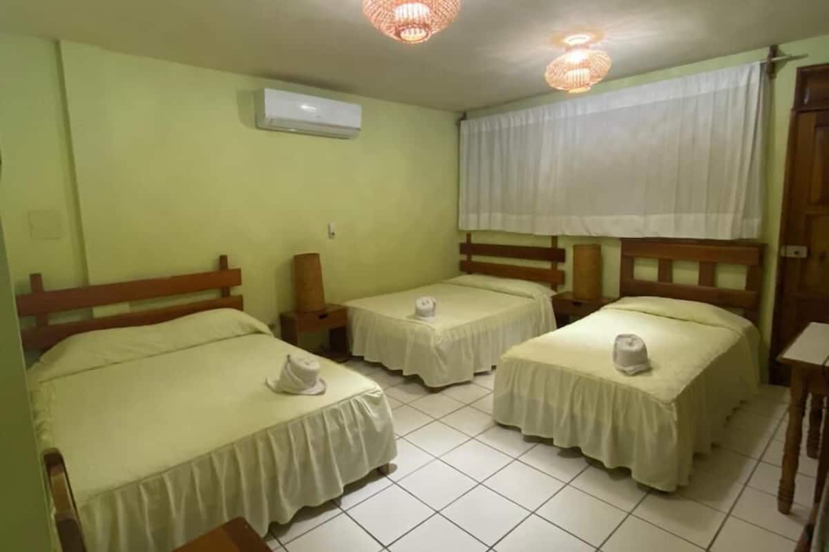 Una habitación con cuatro camas, una mesita de madera y un ventilador de techo.