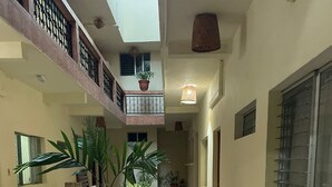 A spacious indoor area with a tiled floor, a wooden bench, several potted plants, and a dining area with chairs and a table. - Nakum Hotel (Flores)