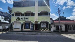 A two-story building with the sign "Nakum Hotel" on the ground floor. - Nakum Hotel (Flores)