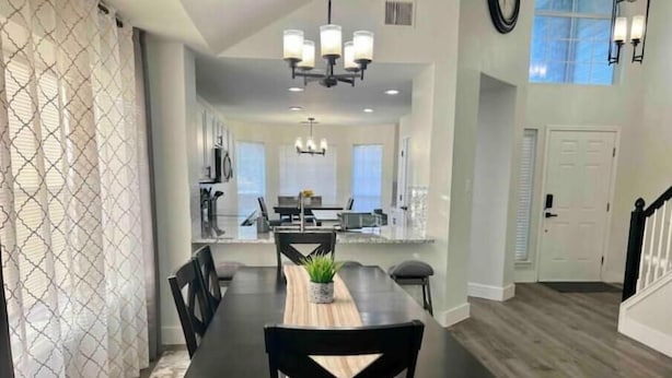A modern dining area with a long table, black chairs, and a chandelier.