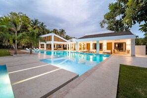A modern house with a swimming pool, outdoor seating, and palm trees. - Casa Mangos Casa de Campo DR  (La Romana)
