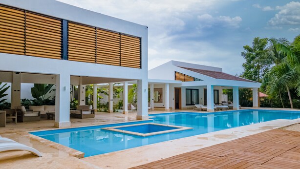 A modern resort with a large pool, outdoor seating, and lush tropical plants. - Casa Mangos Casa de Campo DR  (La Romana)
