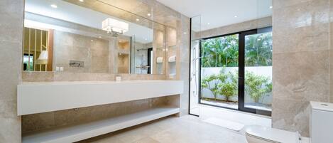 A modern bathroom with a large mirror, a white vanity, and a toilet.