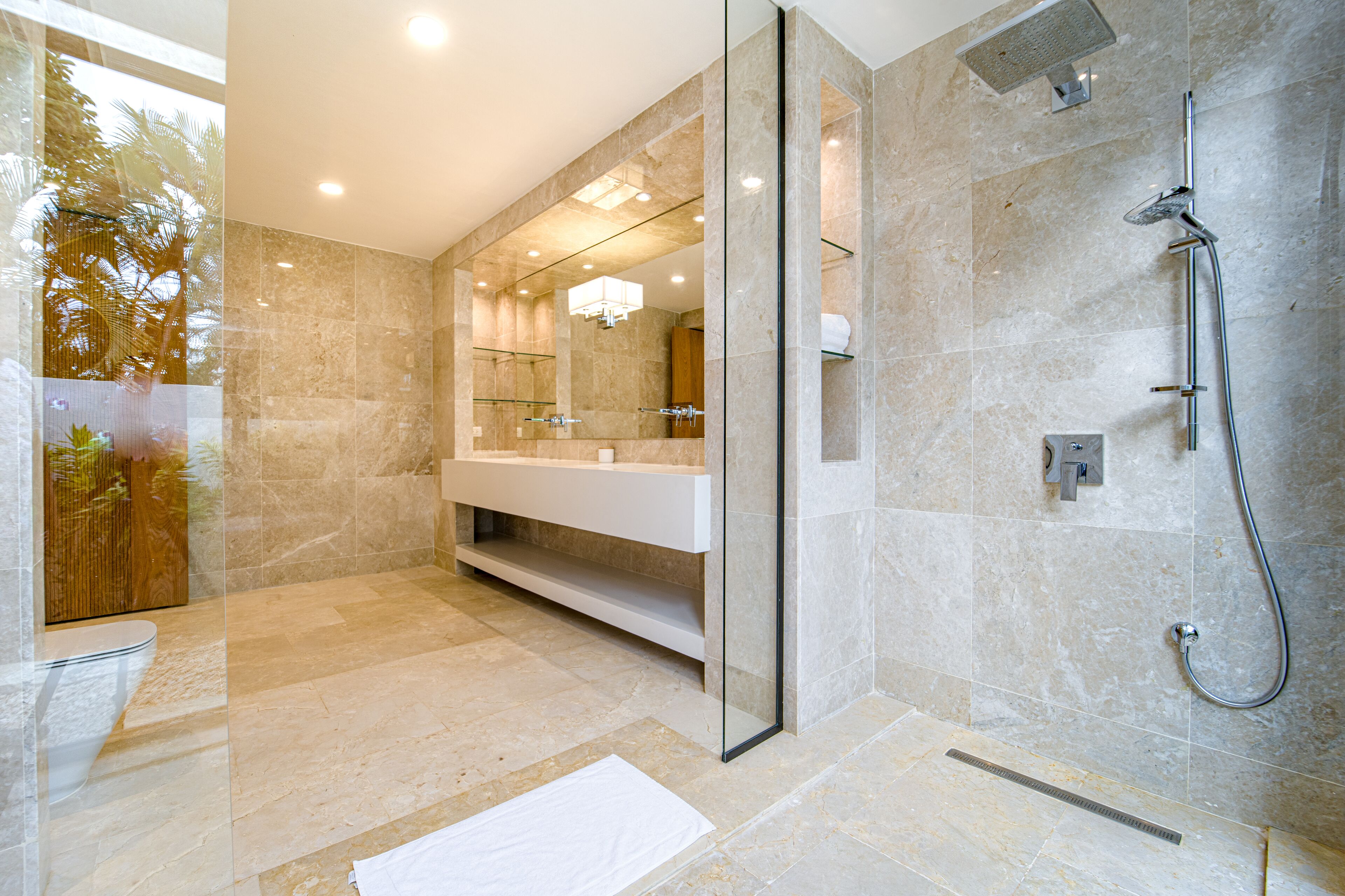 A modern bathroom with a glass-enclosed shower, a white vanity, and a large mirror.