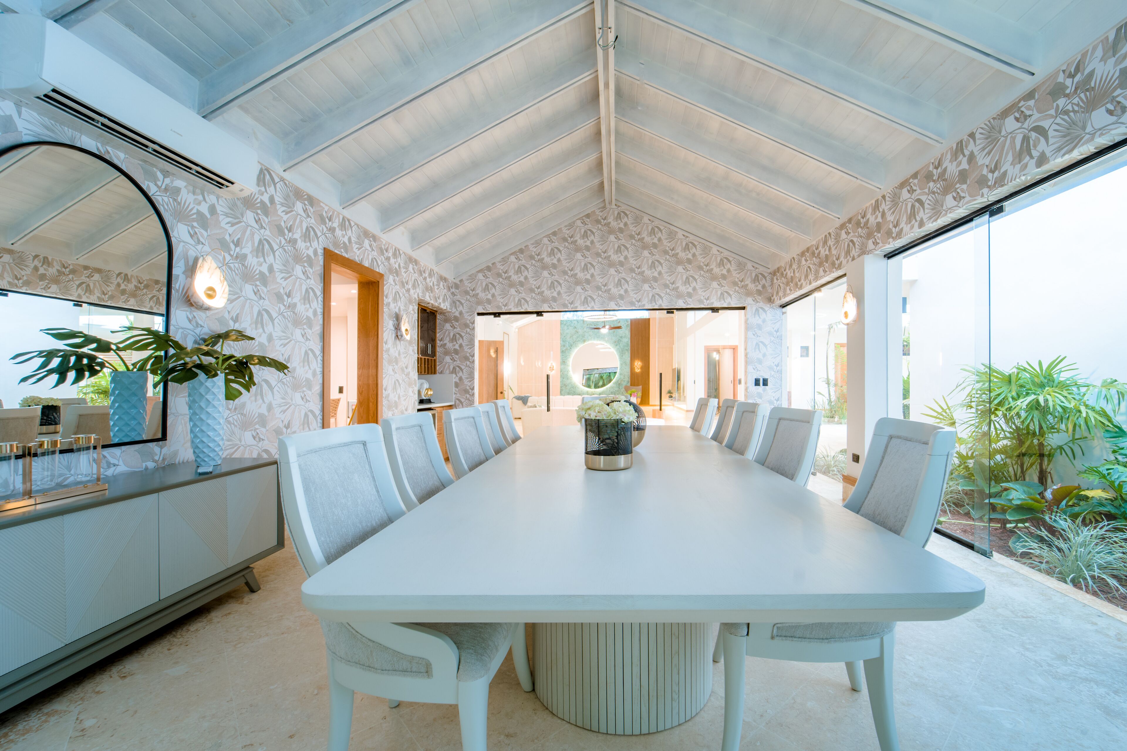 A spacious conference room with a long table, comfortable chairs, and a large mirror on one wall.