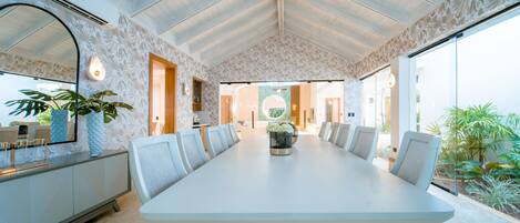 A spacious conference room with a long table, comfortable chairs, and a large mirror on one wall.
