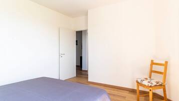 Ein Schlafzimmer mit einem Bett, einem Holzstuhl und einer Tür zu einem anderen Raum.