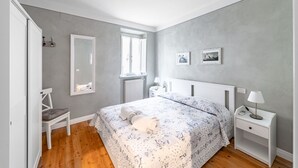 A bedroom with a bed, a nightstand, a chair, a window, and a radiator. - GuestHost - Modern Apartment in the heart of Lucca! (Lucca)