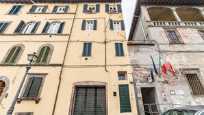 A multi-story building with a yellow facade, green shutters, and a visible door. - GuestHost - Modern Apartment in the heart of Lucca! (Lucca)