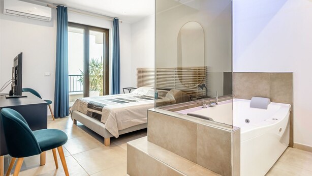 Ein modernes Hotelzimmer mit einem Bett, einem Schreibtisch, einem Stuhl, einer Badewanne und einem großen Fenster.