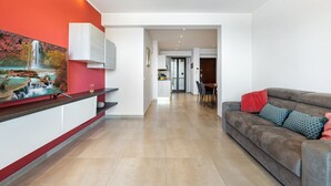 Ein modernes Wohnzimmer mit einer Couch, einem Essbereich und einer Küche mit weißen Schränken.