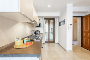 A modern kitchen with a gas stove, a coffee machine, and a small dining area.